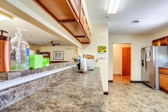 kitchen featuring ceiling fan, visible vents, stainless steel refrigerator with ice dispenser, and brown cabinets