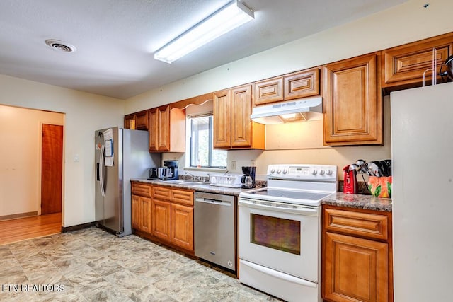 kitchen with visible vents, brown cabinets, stainless steel appliances, under cabinet range hood, and a sink