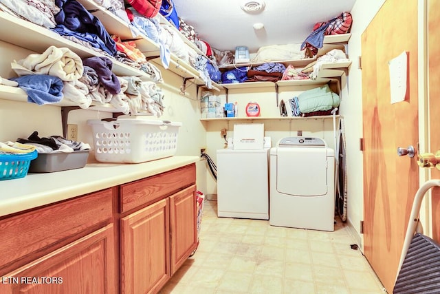 clothes washing area featuring cabinet space, washer and clothes dryer, and light floors
