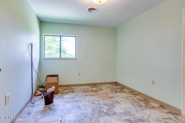 spare room with stone finish flooring, baseboards, and visible vents