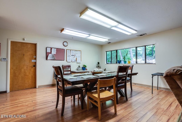 dining room featuring light wood finished floors, baseboards, and visible vents