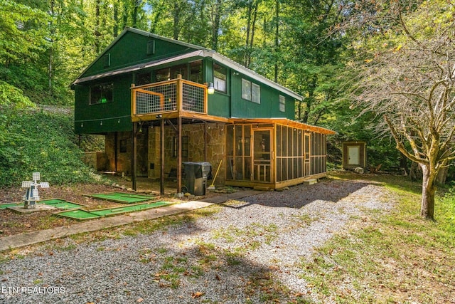 back of property with a balcony and a sunroom