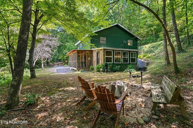 rear view of property with a fire pit and a sunroom