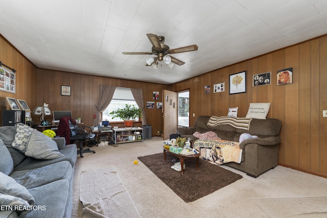 carpeted living room featuring ceiling fan and wooden walls