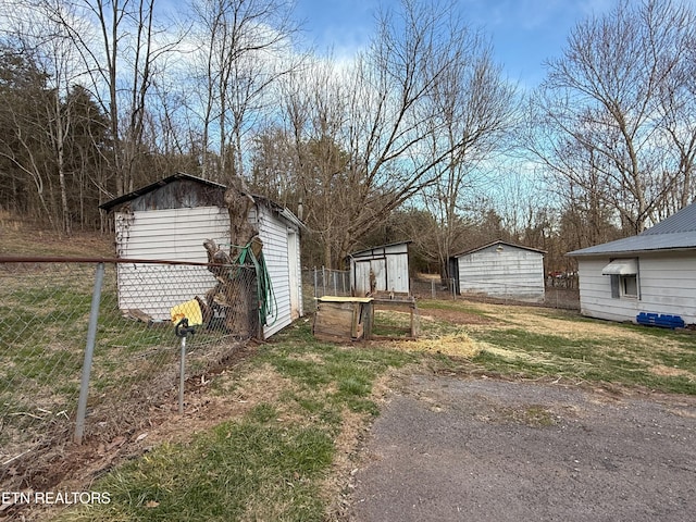 view of yard featuring a garage, an outdoor structure, fence, and a shed