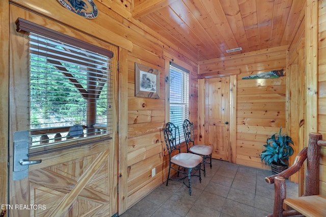 sitting room with tile patterned floors, wooden ceiling, and wood walls