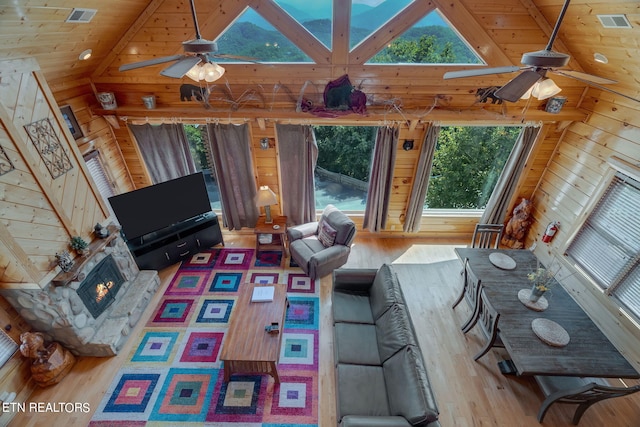 living room with hardwood / wood-style floors, wood walls, lofted ceiling, ceiling fan, and wood ceiling