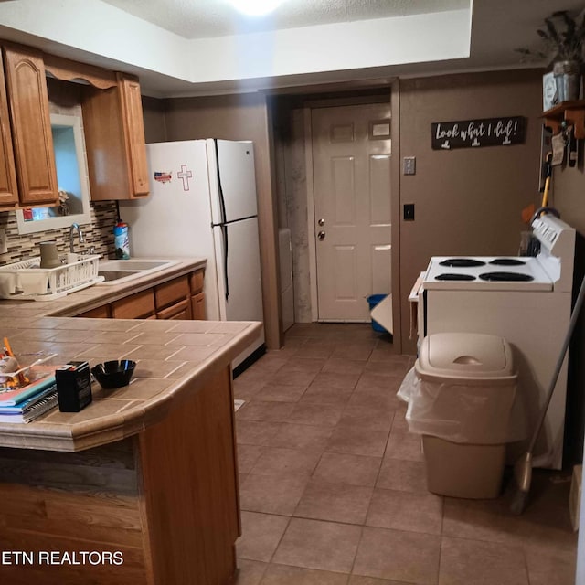 kitchen featuring tile counters, decorative backsplash, tile patterned flooring, sink, and a raised ceiling