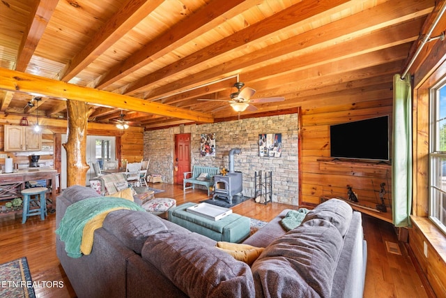 living room with a wood stove, plenty of natural light, ceiling fan, and wood-type flooring