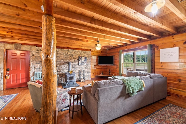 living room with wood ceiling, wood-type flooring, ceiling fan, and a wood stove