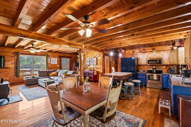 dining space with dark hardwood / wood-style floors, beamed ceiling, wood ceiling, ceiling fan, and wooden walls