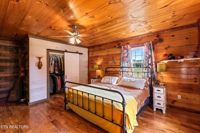 bedroom with a barn door, wood ceiling, and hardwood / wood-style flooring