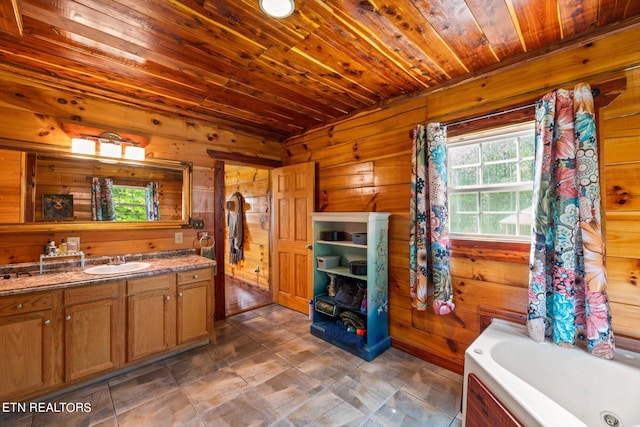 bathroom with vanity, wood ceiling, wooden walls, and a bathtub