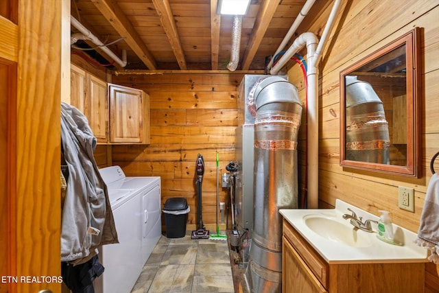 clothes washing area featuring wood walls, independent washer and dryer, wooden ceiling, and sink