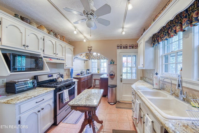 kitchen with white cabinetry, gas range, rail lighting, and ceiling fan