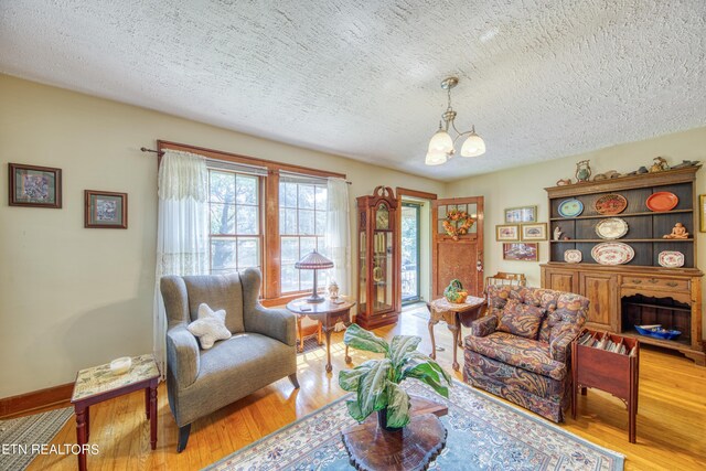 living room with hardwood / wood-style flooring, an inviting chandelier, and a textured ceiling