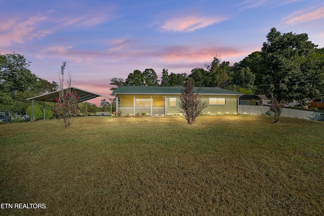 ranch-style house with a lawn, a carport, and covered porch