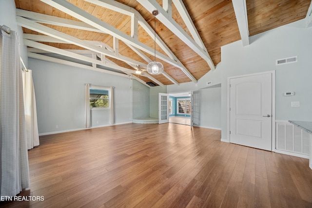 unfurnished living room with hardwood / wood-style floors, beam ceiling, and high vaulted ceiling