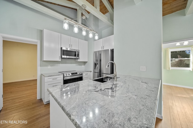 kitchen featuring white cabinetry, high vaulted ceiling, light stone counters, and stainless steel appliances