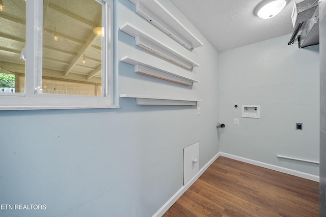 clothes washing area featuring electric dryer hookup, washer hookup, hardwood / wood-style floors, and a textured ceiling