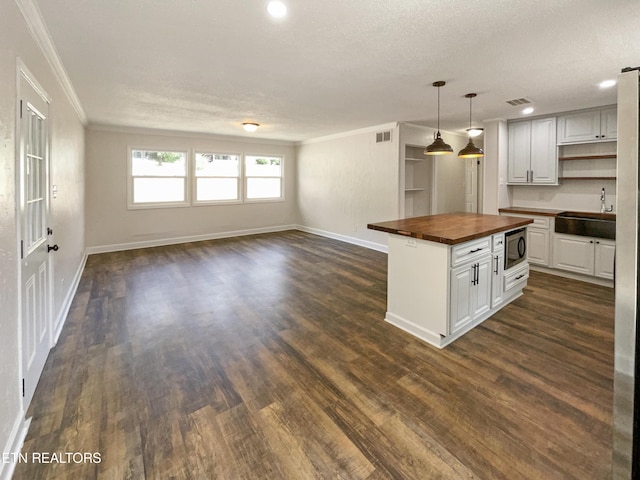 kitchen with dark wood-type flooring, butcher block countertops, a sink, open floor plan, and built in microwave