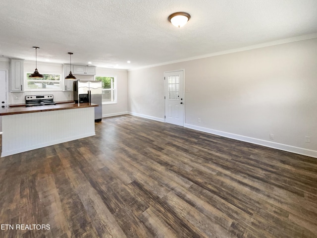 kitchen featuring dark wood finished floors, ornamental molding, butcher block countertops, stainless steel appliances, and open floor plan