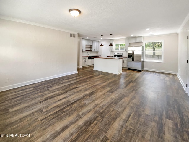 unfurnished living room with visible vents, baseboards, ornamental molding, dark wood-style flooring, and a sink