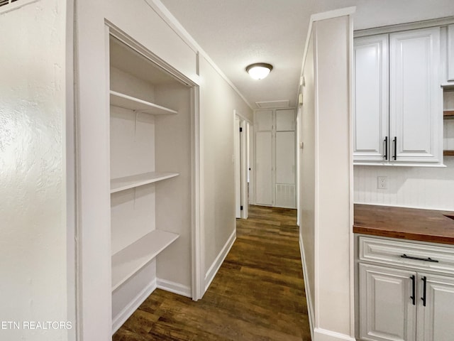 hallway featuring visible vents, dark wood-type flooring, and baseboards