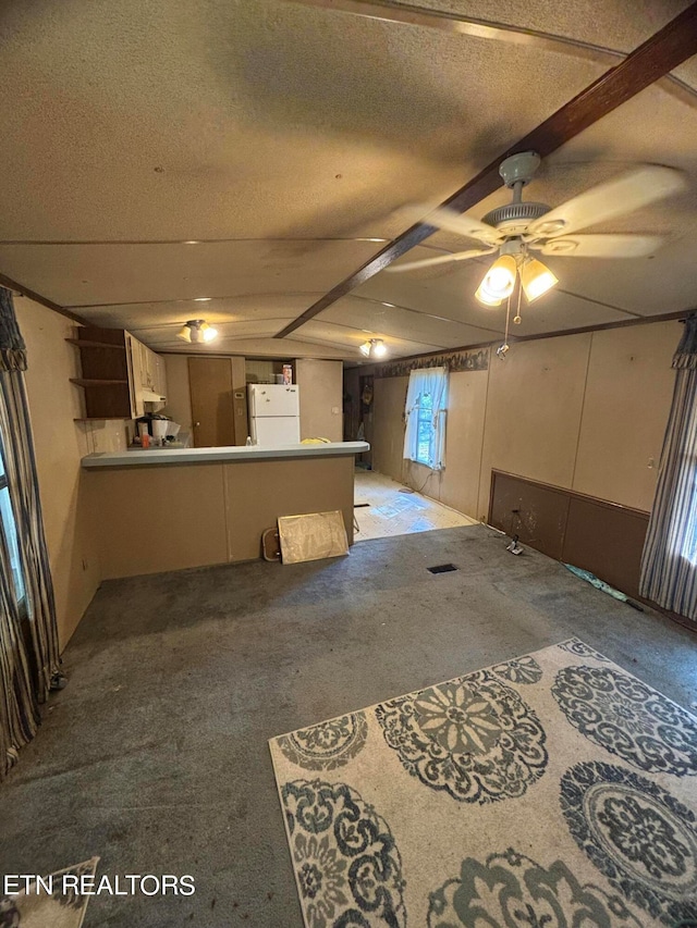 interior space with ceiling fan, white refrigerator, kitchen peninsula, a textured ceiling, and light carpet