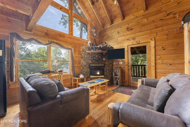 living room featuring wooden ceiling, a stone fireplace, beamed ceiling, light hardwood / wood-style floors, and wooden walls