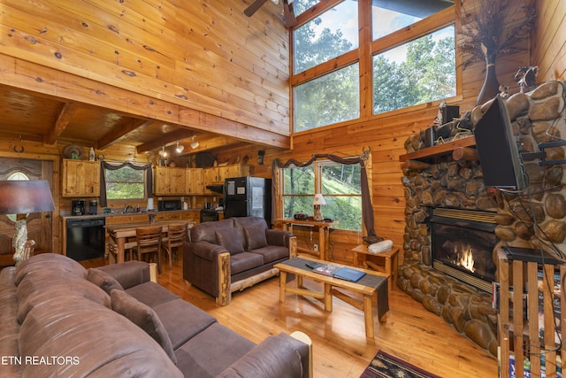 living room featuring a high ceiling, light hardwood / wood-style flooring, beamed ceiling, a fireplace, and wood ceiling