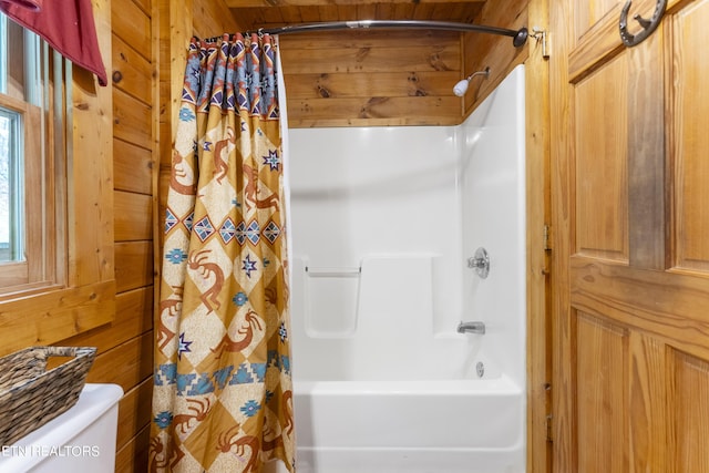 bathroom featuring toilet, shower / tub combo with curtain, and wooden walls