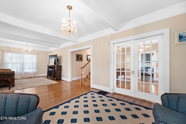 living room featuring wood-type flooring, beam ceiling, an inviting chandelier, and french doors