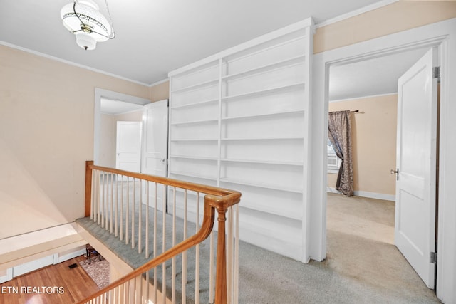 corridor featuring ornamental molding and light colored carpet