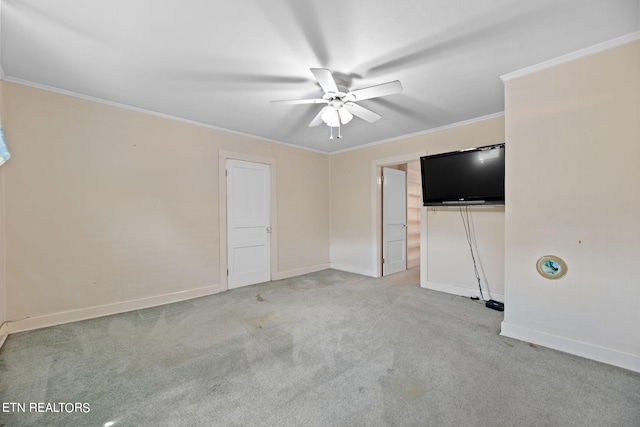 empty room featuring ceiling fan, light colored carpet, and crown molding