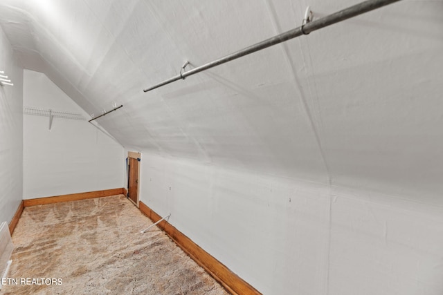 walk in closet with light colored carpet and lofted ceiling