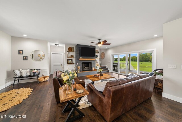 living room with a large fireplace, ceiling fan, and dark hardwood / wood-style floors