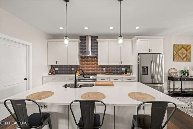 kitchen featuring a breakfast bar, appliances with stainless steel finishes, wall chimney exhaust hood, and decorative light fixtures