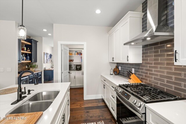 kitchen featuring stainless steel range with gas stovetop, decorative light fixtures, dark hardwood / wood-style flooring, sink, and wall chimney exhaust hood