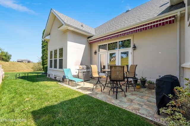 rear view of house with a lawn and a patio