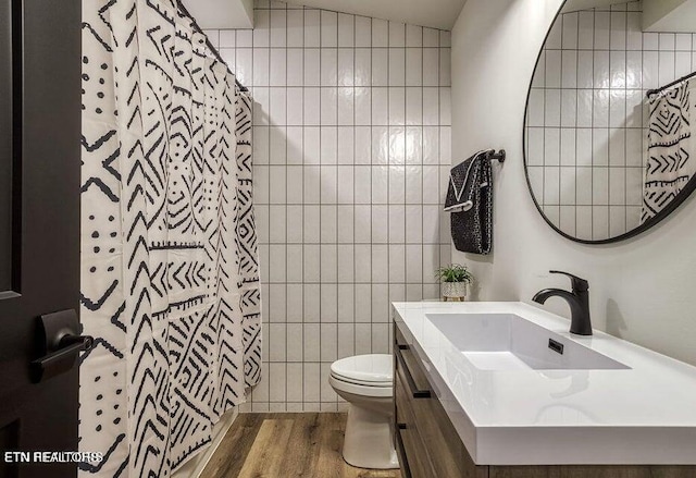 bathroom featuring hardwood / wood-style floors, toilet, lofted ceiling, tile walls, and vanity