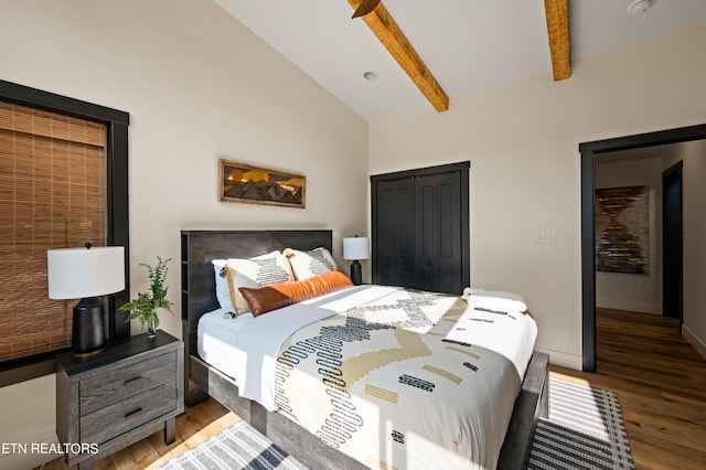 bedroom with a closet, hardwood / wood-style flooring, and vaulted ceiling with beams