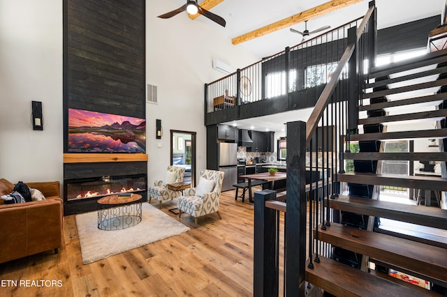 living room featuring plenty of natural light, ceiling fan, a towering ceiling, and hardwood / wood-style floors