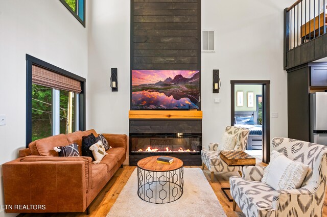 living room with plenty of natural light, light hardwood / wood-style floors, and a towering ceiling