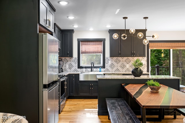 kitchen featuring light hardwood / wood-style flooring, light stone counters, stainless steel appliances, sink, and pendant lighting