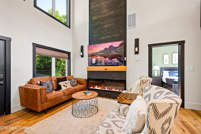 living room with light hardwood / wood-style flooring and a high ceiling