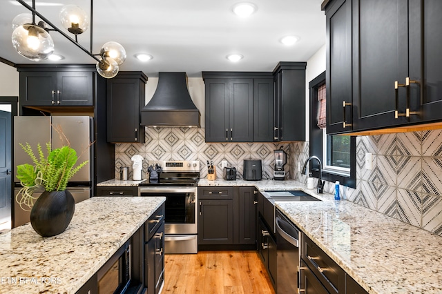 kitchen featuring custom range hood, decorative light fixtures, stainless steel appliances, light hardwood / wood-style floors, and sink