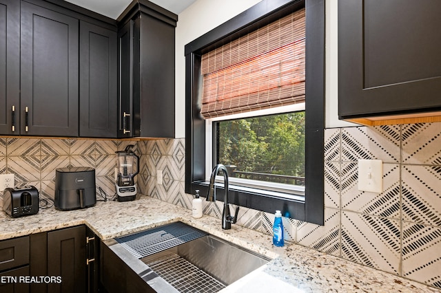 kitchen featuring sink, light stone countertops, and decorative backsplash