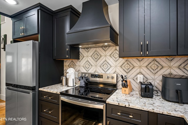 kitchen featuring light stone countertops, hardwood / wood-style floors, stainless steel appliances, decorative backsplash, and custom exhaust hood