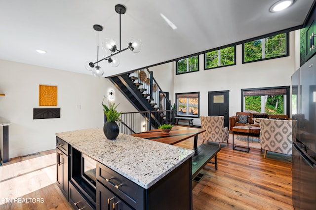 kitchen featuring decorative light fixtures, a kitchen island, light stone countertops, dark hardwood / wood-style floors, and stainless steel microwave